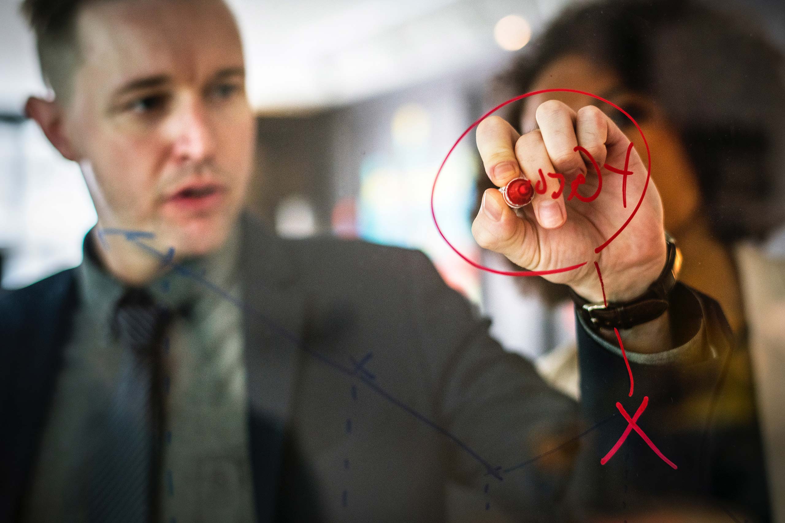 Sharing Privileged Accounts With Third Parties A man drawing with a red pen on a pane of glass, seen from the other side of the glass